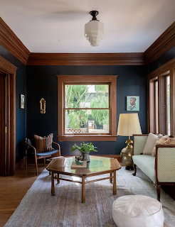 Cozy sitting room with navy walls, wood trim, window, coffee table, and light rug