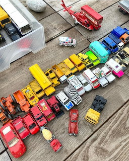Overhead view of colorful vintage toy cars arranged in rainbow gradient on wooden surface