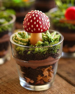 Layered chocolate dessert in glass with red mushroom decoration and green moss garnish