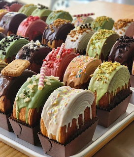 Rows of gourmet chocolate-covered desserts with varied toppings including pistachios, coconut, and sprinkles