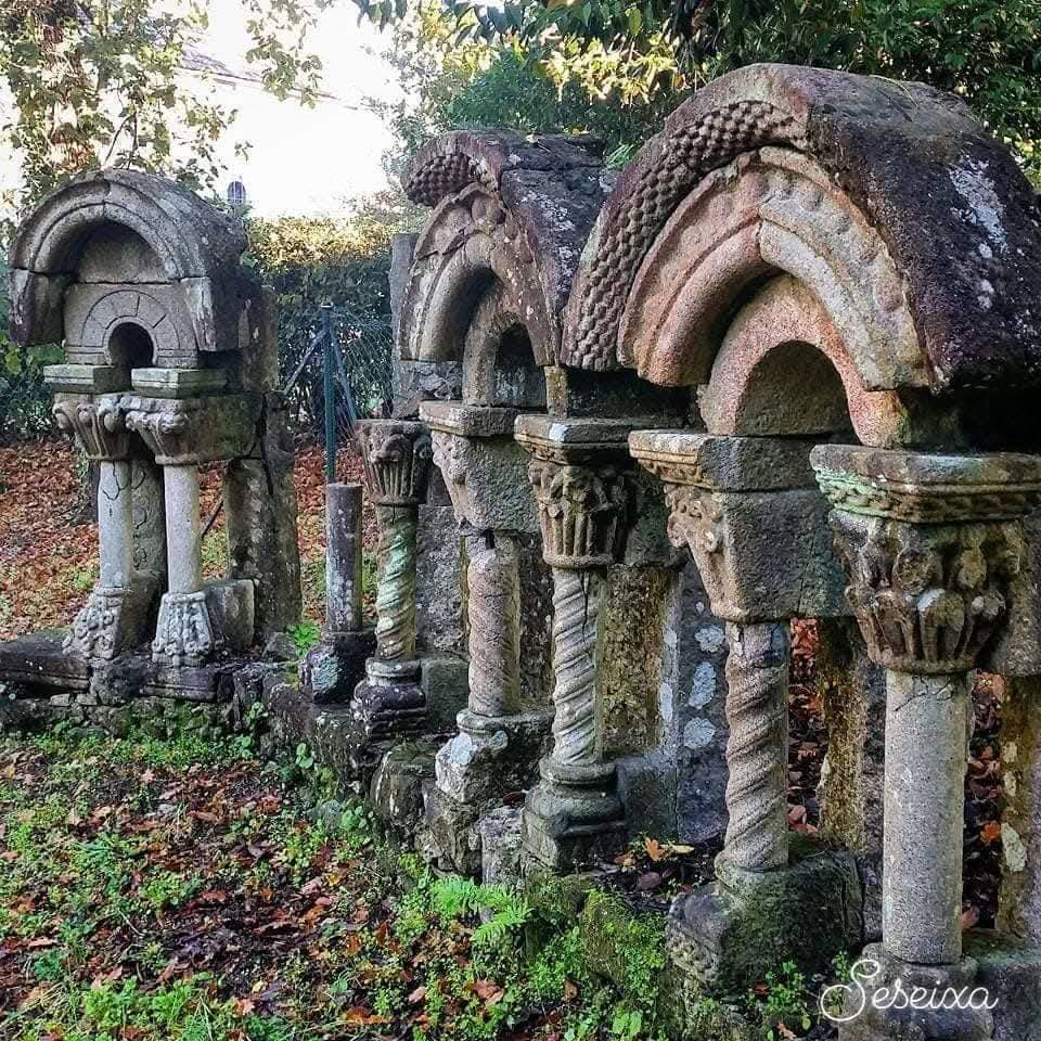 Old stone arches and carved columns in a leafy overgrown garden