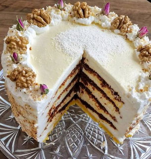 Layered cake with white frosting, walnuts, and purple flowers, showing interior layers with dark filling