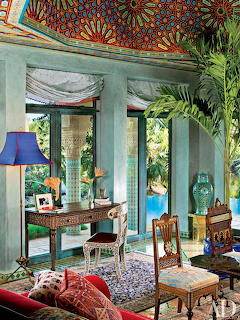 Ornate Middle Eastern style room with colorful painted ceiling, decorative furniture, and tropical garden view