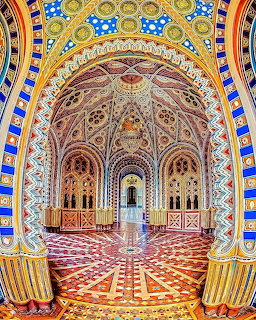 Ornate palace interior with colorful Moorish arches, patterned tiles, and geometric floor