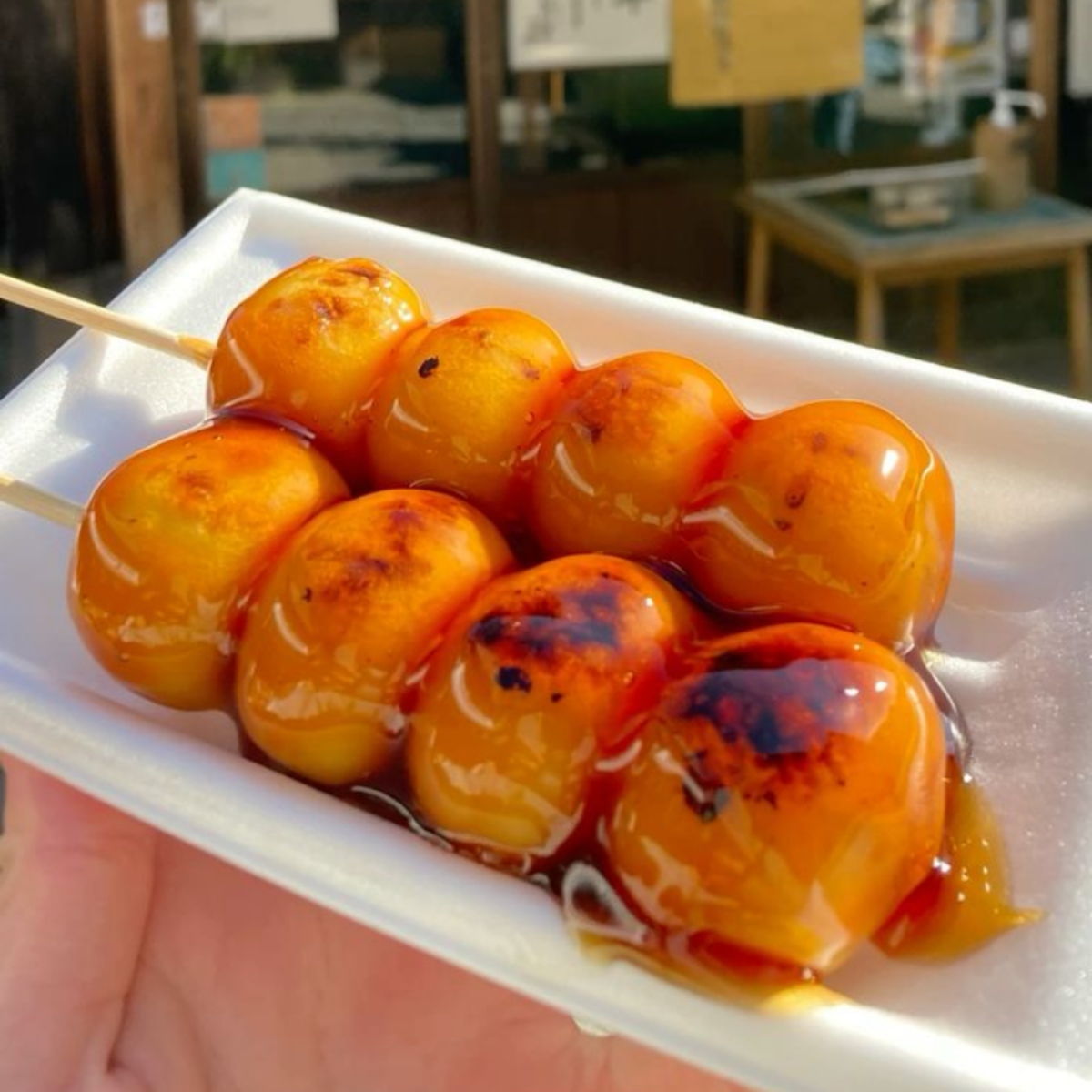 Skewered glazed dango dumplings on a white tray with sweet soy sauce
