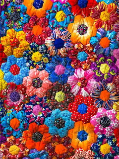 Dense arrangement of colorful handmade fabric flowers with various patterns including polka dots and stripes