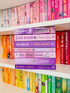 Bookshelf with colorful paperback books arranged in pink, orange, purple, and green rows