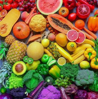 Vibrant rainbow arrangement of fresh fruits and vegetables organized by color from red through orange, yellow, green to purple