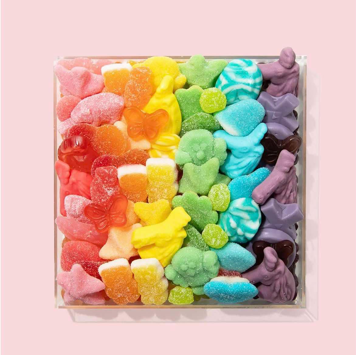 Rainbow gradient of colorful sour gummy candies in clear container