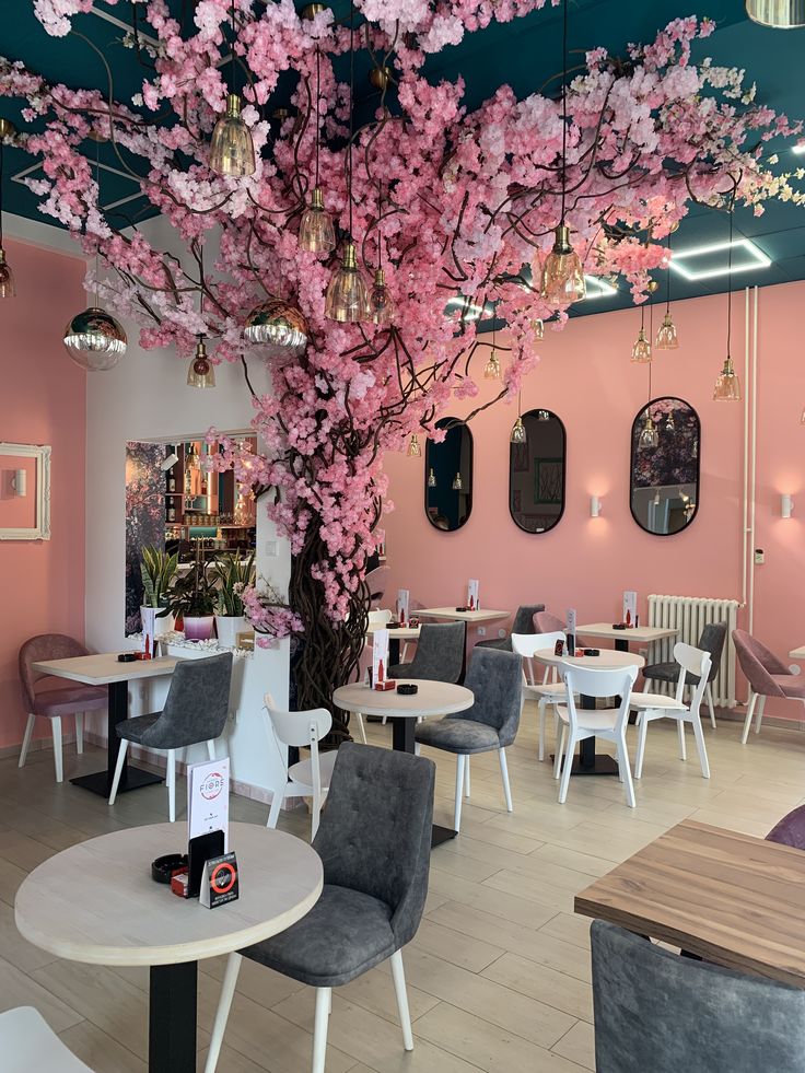Cafe interior with a large tree growing inside among wooden tables and warm lighting
