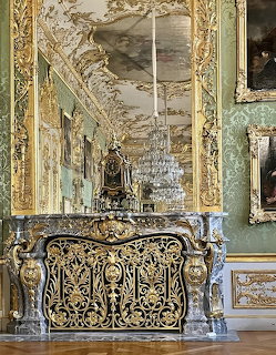 Opulent Baroque palace interior with gilded console table, crystal chandelier, and ornate gold mirror