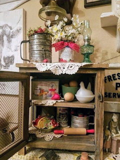 Rustic wooden kitchen cabinet with vintage utensils, tins, oil lamp, and farmhouse decorations