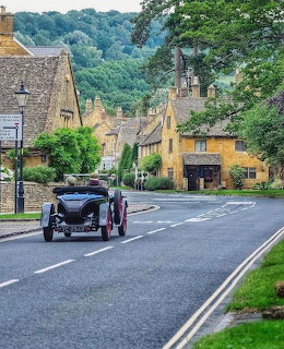 Historic Cotswolds village street with stone cottages and vintage car in Broadway
