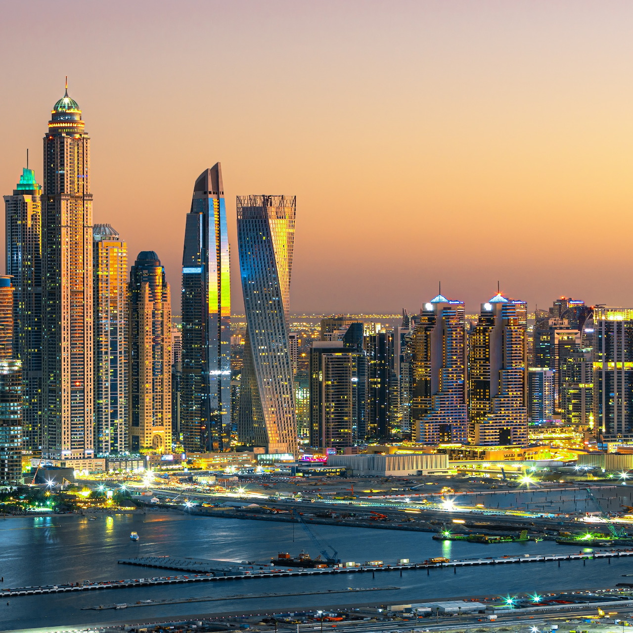 Dubai Marina skyline at twilight with lit skyscrapers beside the waterfront