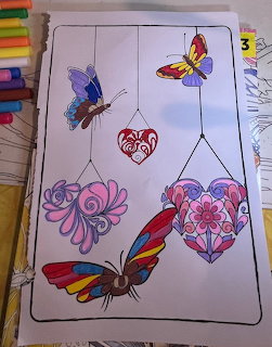 Colorful butterflies and ornate hearts with swirls in pink, purple, and red tones on white background