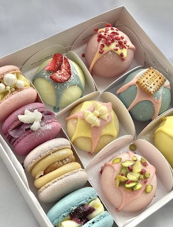 Colorful macarons and round desserts in pastel shades arranged in compartments of a white box