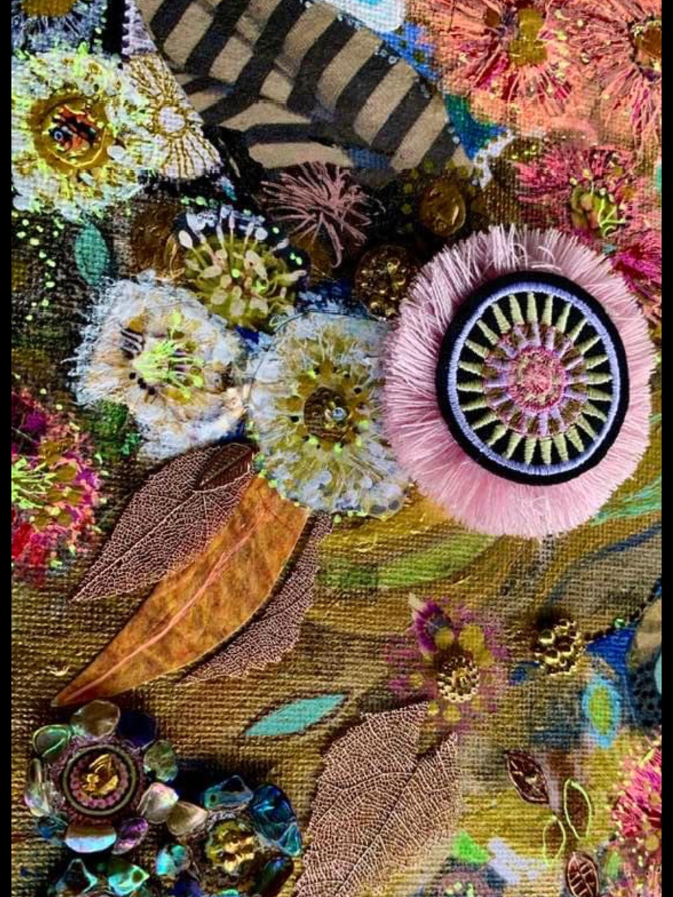 Close-up of mixed-media embroidery with flowers, feathers, beads, and decorative buttons on textured fabric