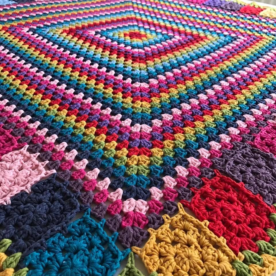 Rainbow crochet blanket with concentric diamond squares in vibrant multicolor yarn