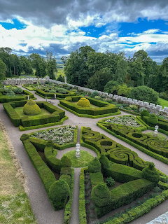 Ornate formal garden with geometric topiary hedges and sculpted bushes viewed from above