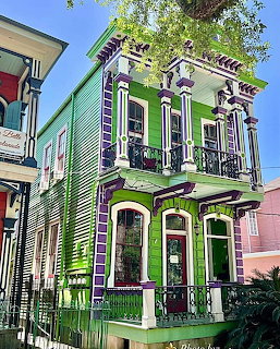 Bright green Victorian house with purple decorative trim and ornate balconies