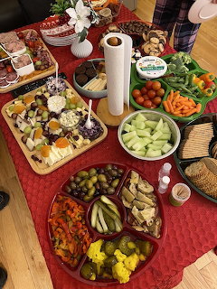 Overhead view of table with multiple food platters, vegetables, dips, and holiday decorations