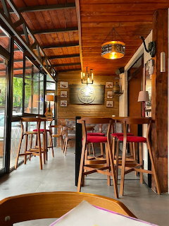 Cozy cafe interior with wooden ceiling, tall tables, colorful chairs, and large windows