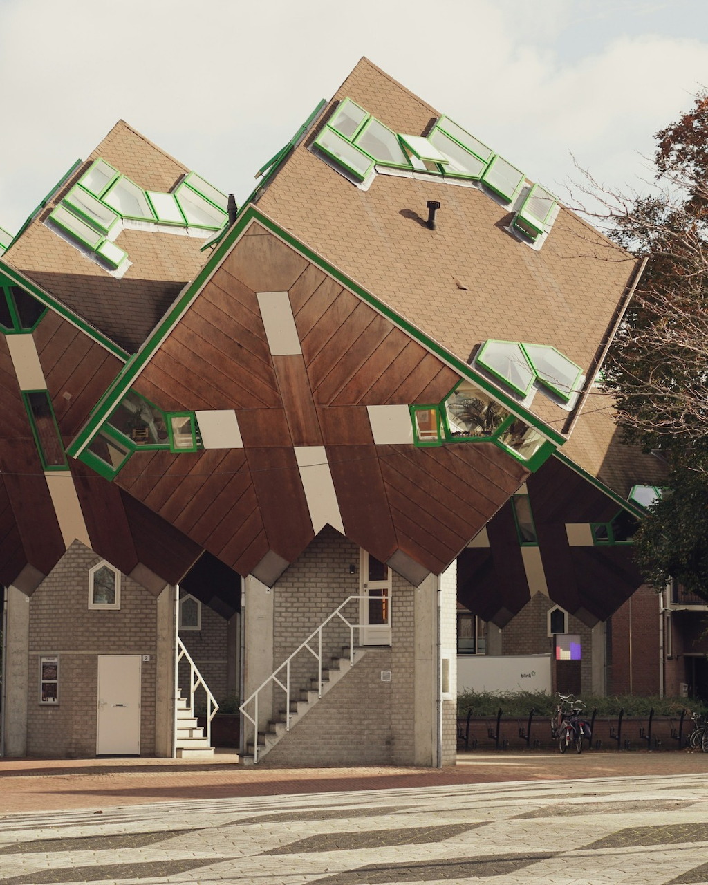 Cube-shaped house tilted at 45 degrees with brick walls and geometric windows in urban setting