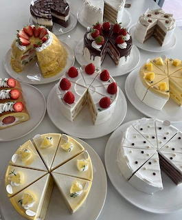 Overhead view of a table with multiple sliced cakes and desserts on white plates