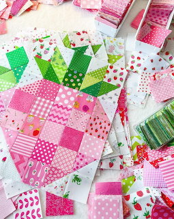 Patchwork quilt blocks in pink and green with assorted fabric patterns and sewing supplies