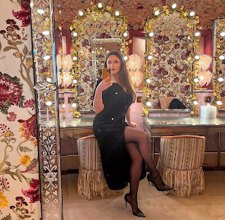 Woman in a black dress taking a mirror selfie at an ornate vanity table