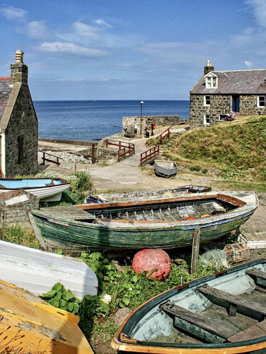 Weathered fishing boats on shore in Crovie village, Scotland, with stone cottages and ocean view