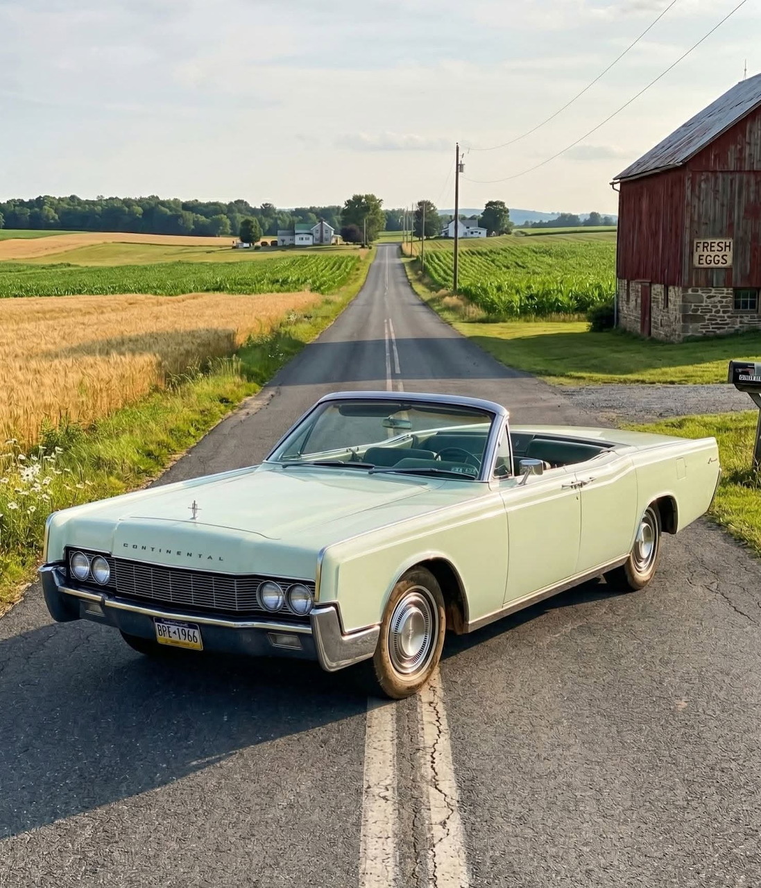 1967 Lincoln Continental convertible in light green on a country road with farmland and red barn in background