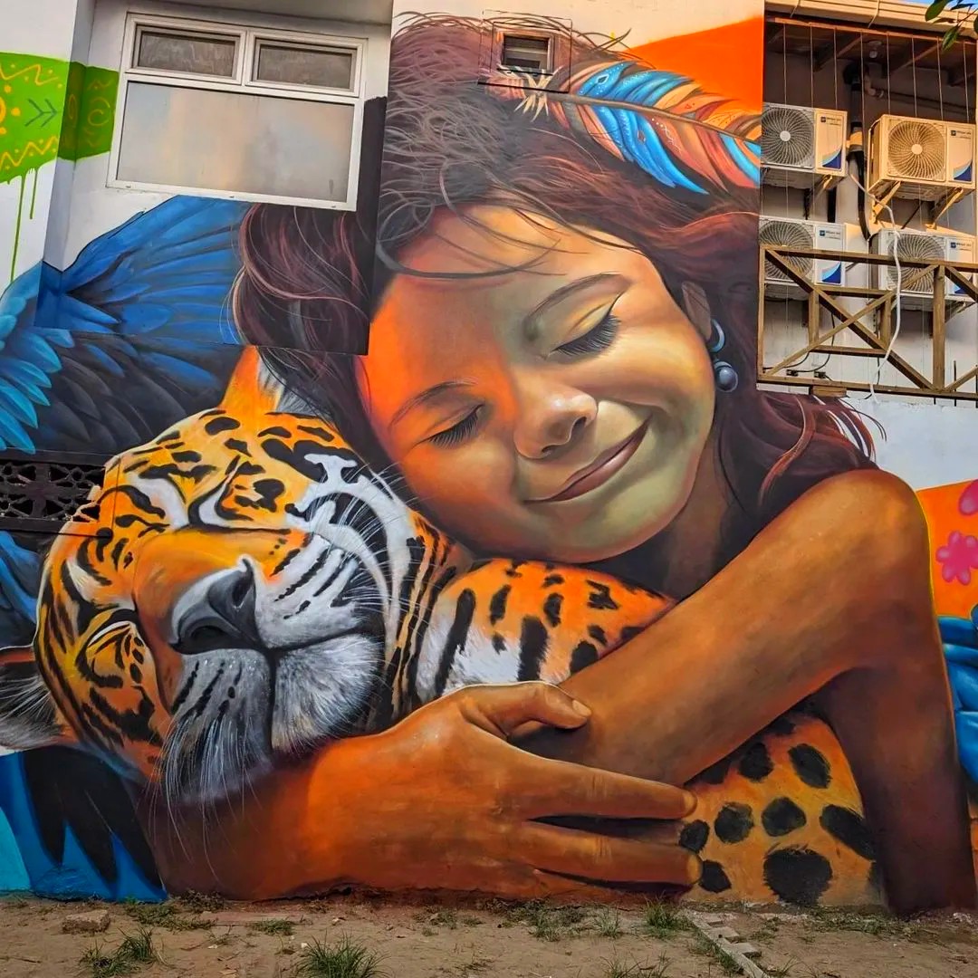 Street art mural showing a girl hugging a tiger painted on a building wall