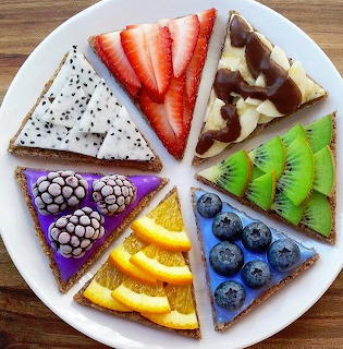 Eight triangular dessert wedges on a white plate, each decorated with different colorful fresh fruits