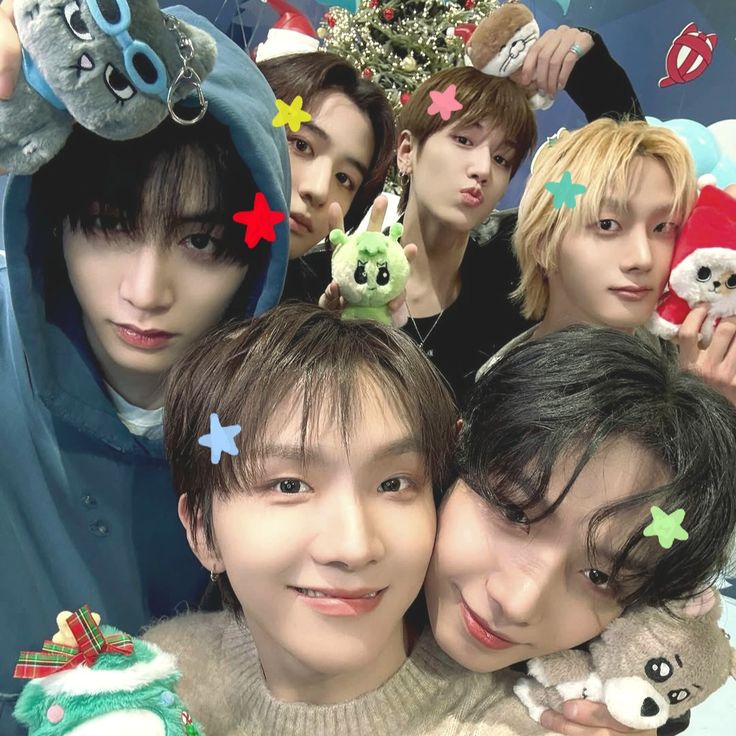 Six young men posing for a close-up selfie with plush toys and colorful star stickers