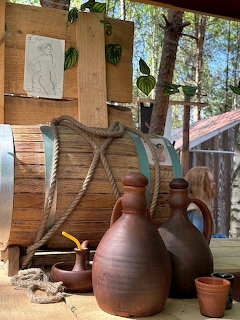 Rustic clay pots and basket beside a wooden wall with a pinned sketch outdoors