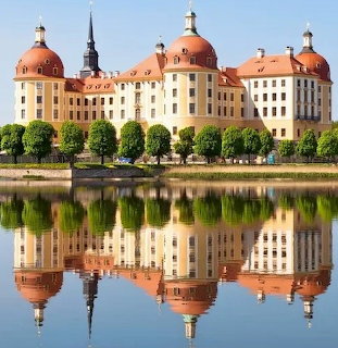 Baroque castle with orange domes mirrored in lake