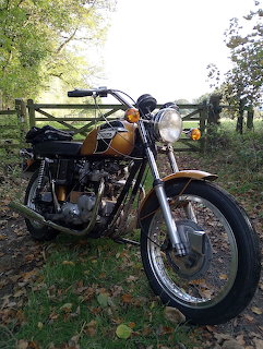 Vintage 1971 Triumph Bonneville motorcycle with chrome fenders and tank parked outdoors on grass