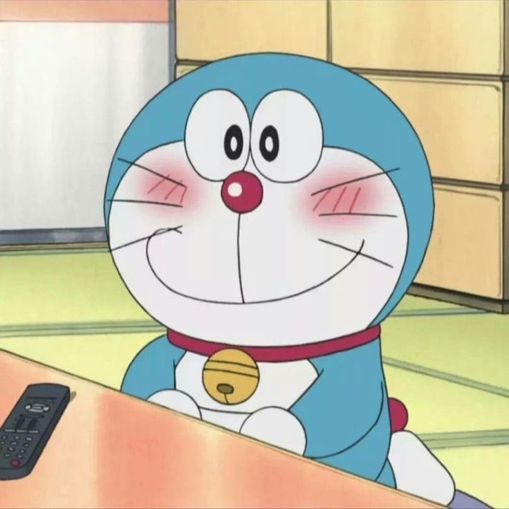 Doraemon smiling with blushing cheeks at a table in a traditional Japanese room