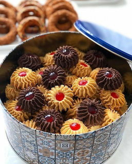 Colorful butter cookies with chocolate and vanilla swirls and red jam centers in decorative tin