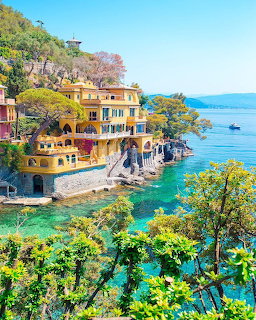 Colorful yellow villas on rocky cliffs overlooking turquoise sea in Portofino, Italy