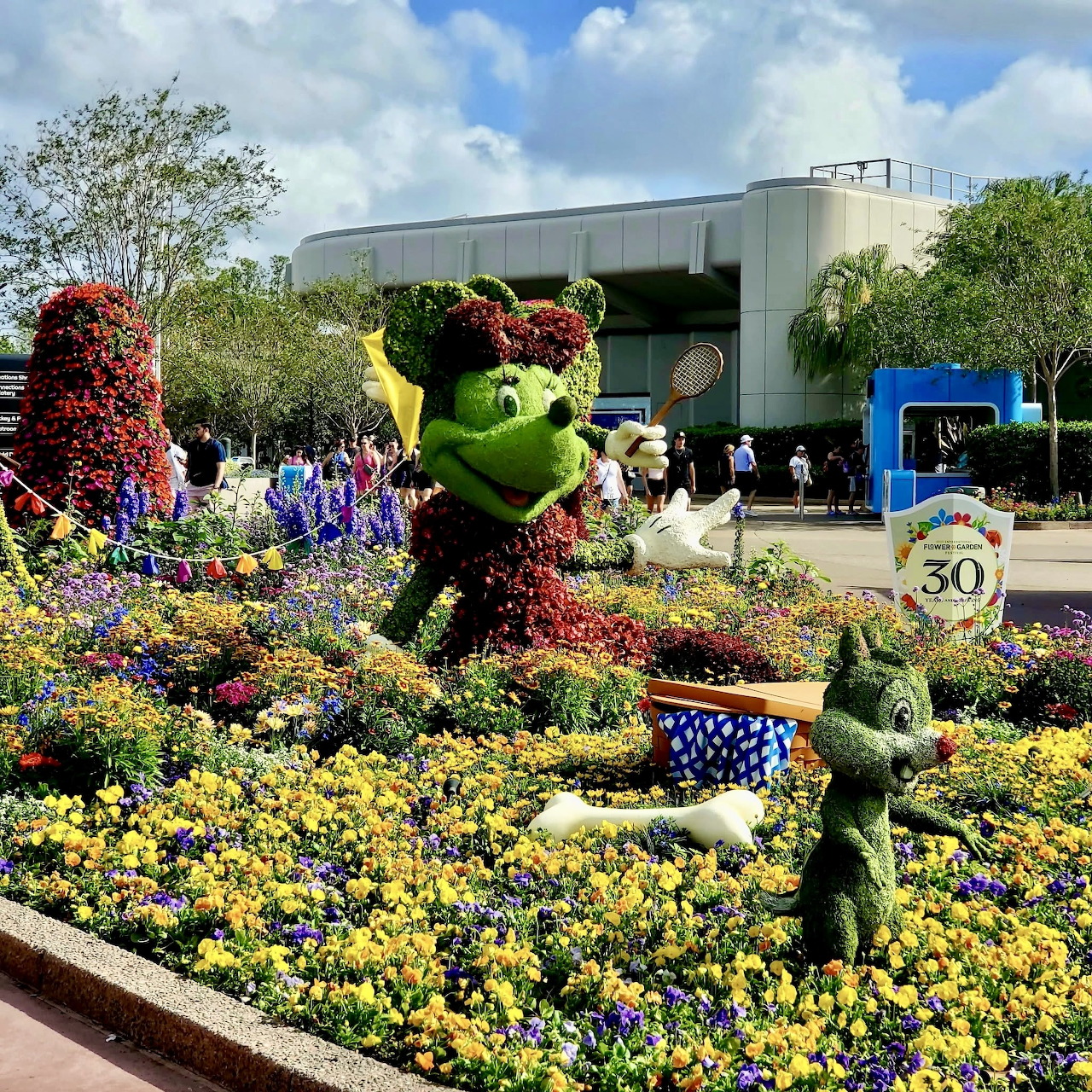 Green topiary characters in colorful flower garden at Epcot theme park