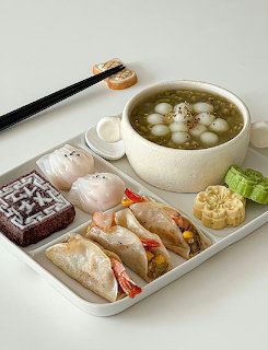Korean meal tray with rice rolls, soup, corn, and vegetables on white background