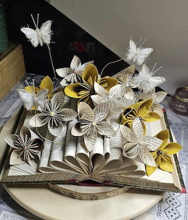 Open book with paper origami flowers and butterflies made from folded book pages in white and yellow colors