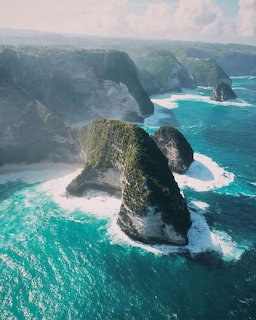 Aerial photograph of rocky coastal cliffs and sea stacks surrounded by turquoise ocean waters