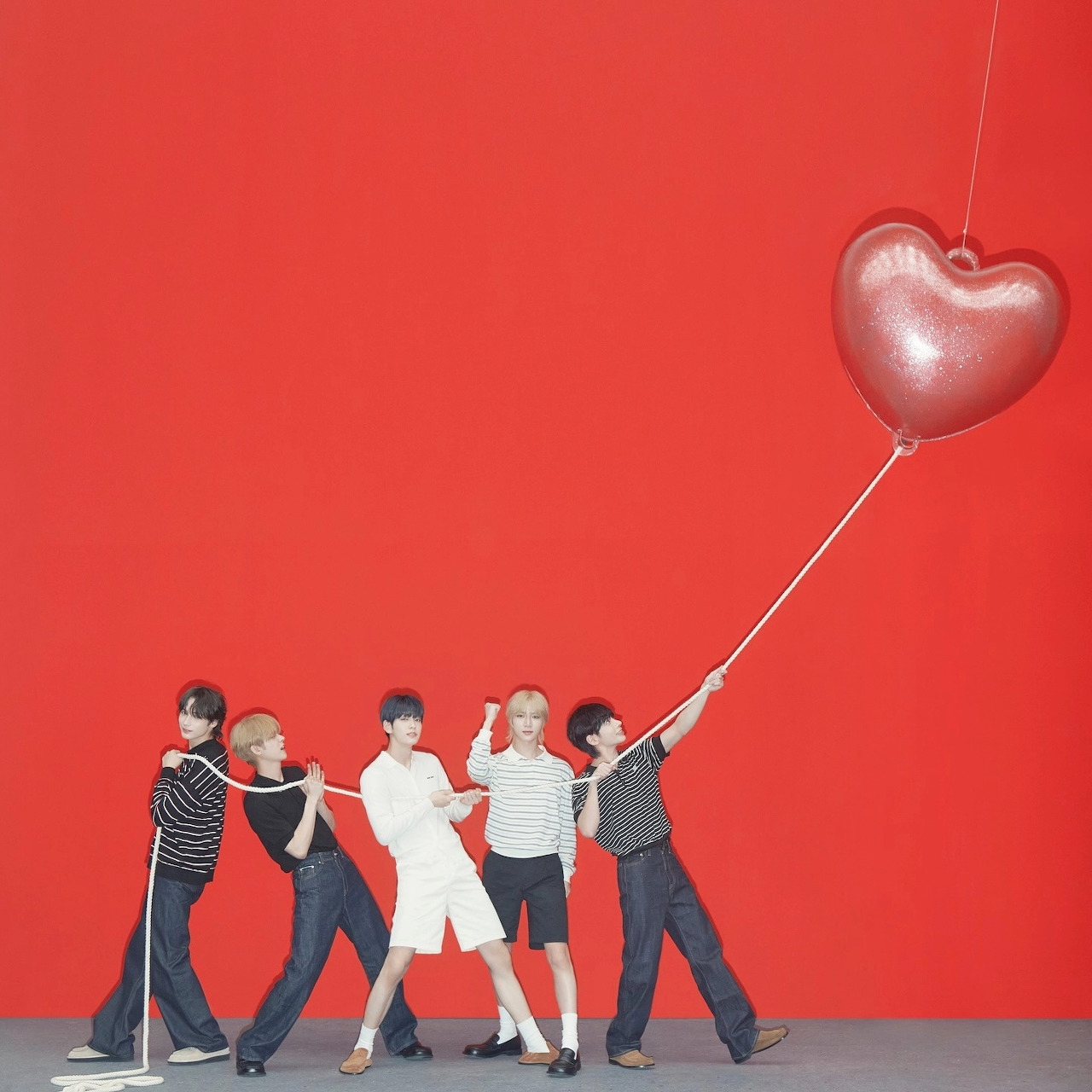 Five young men posing with a heart-shaped balloon against a bright red background