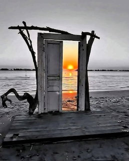 Old door frame on a beach at sunset with orange sun reflected on calm water