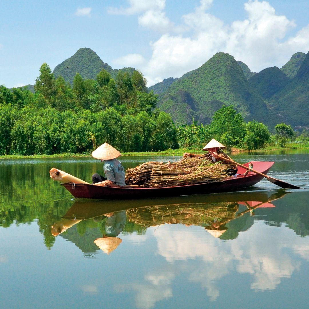 Two wooden boats on a calm river with mountain reflections and lush green trees