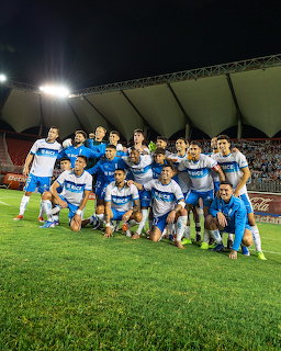 Soccer players posing as a team on a stadium field at night