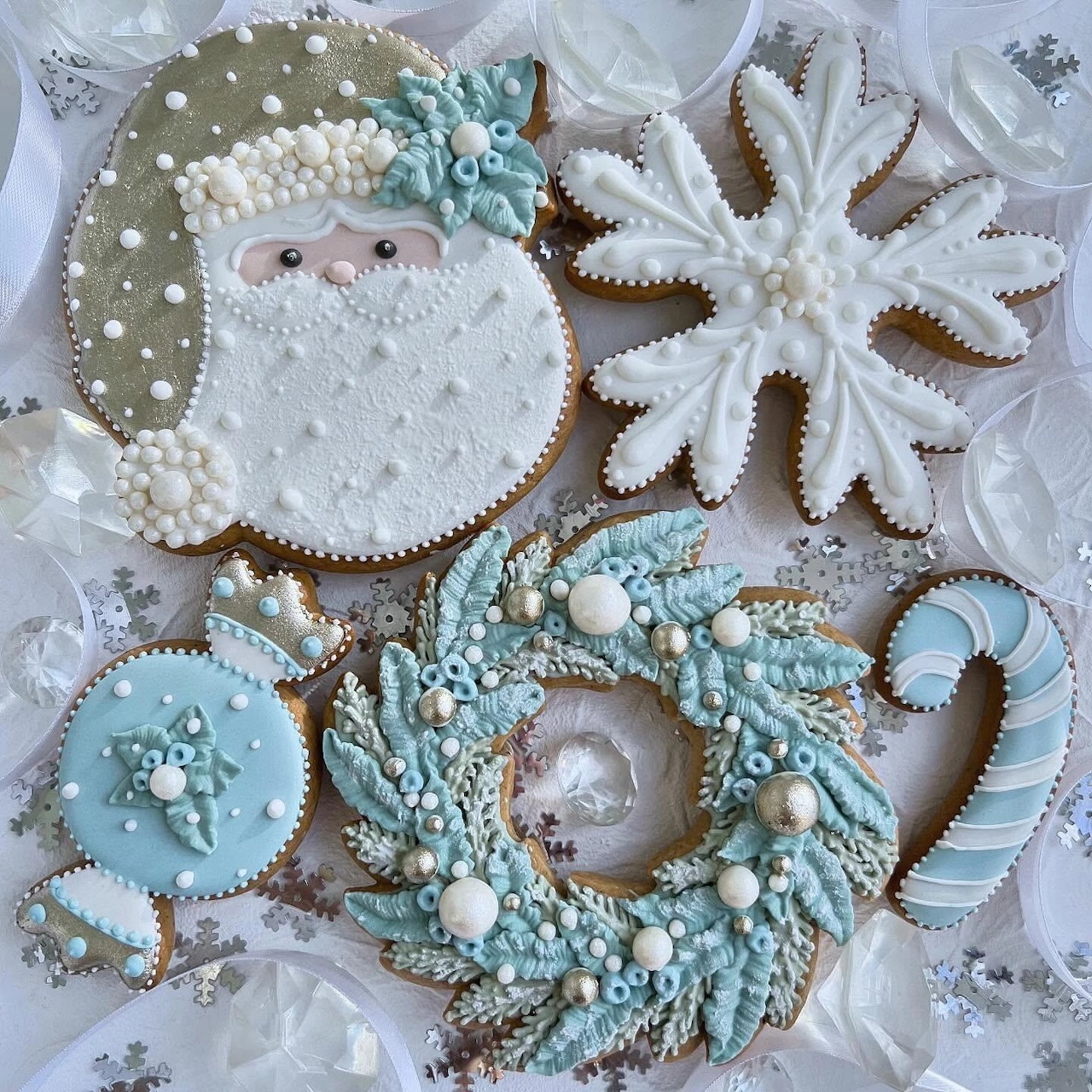 Assorted winter cookies decorated with white and light blue royal icing, pearls, and snowflake patterns